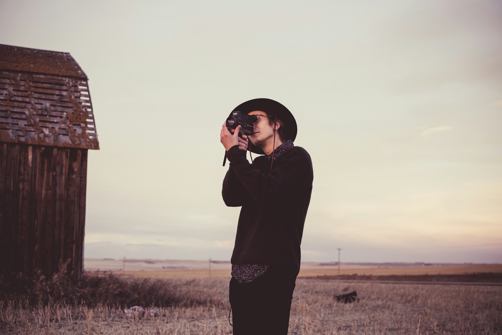 man holding camera near barn house